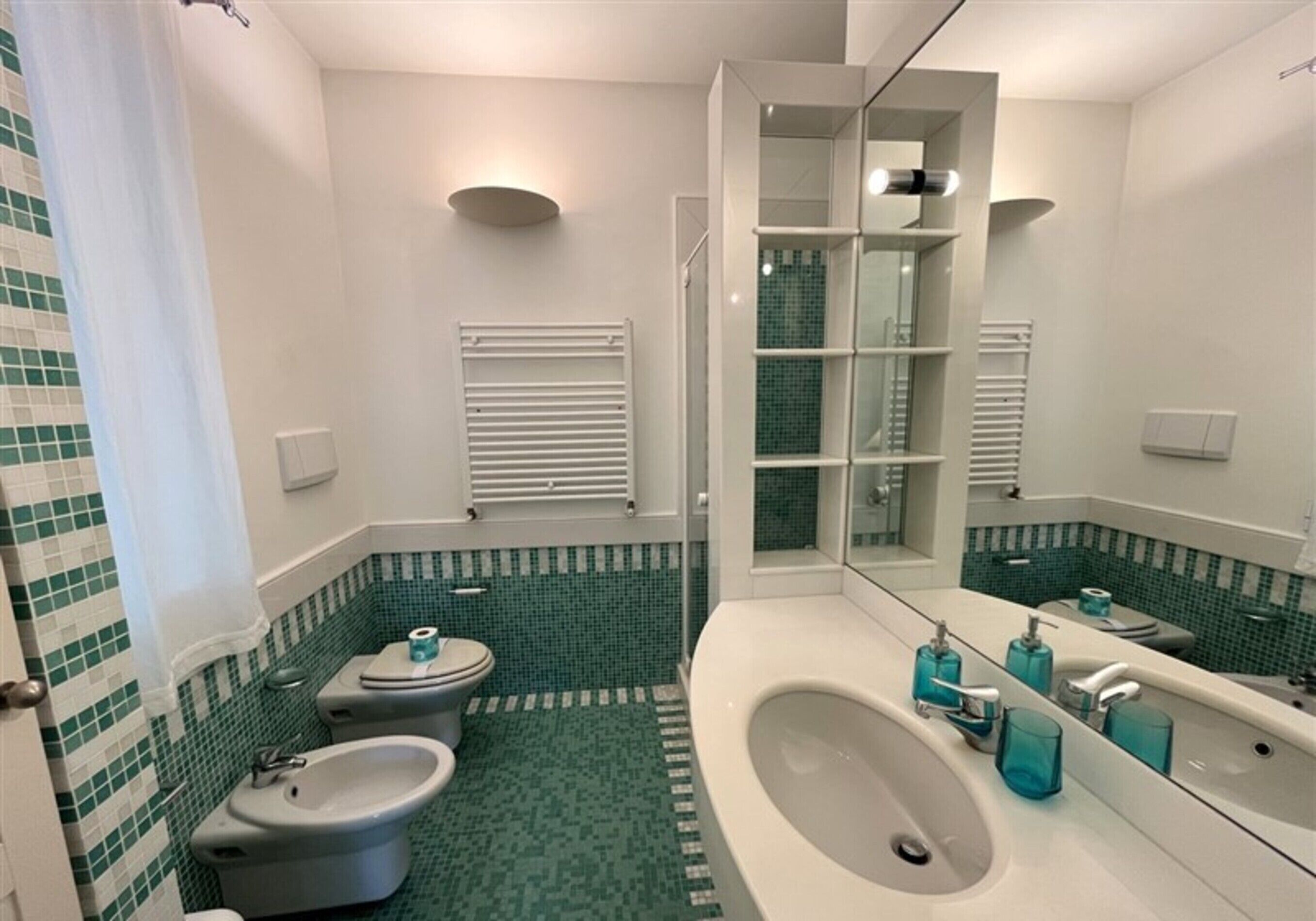 A bathroom with a bidet, toilet, and sink.