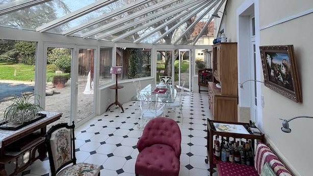 A conservatory with a glass roof, a dining table with chairs, a red sofa, and a patterned armchair. - Old Maison de Maitre with great comfort (Gujan-Mestras)
