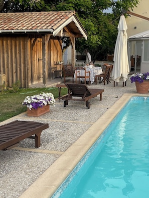A poolside area with a wooden pergola, outdoor seating, and a tiled pool. - Old Maison de Maitre with great comfort (Gujan-Mestras)
