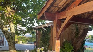 A wooden pergola with a stone pathway leading to it, surrounded by lush greenery and flowering plants. - Old Maison de Maitre with great comfort (Gujan-Mestras)