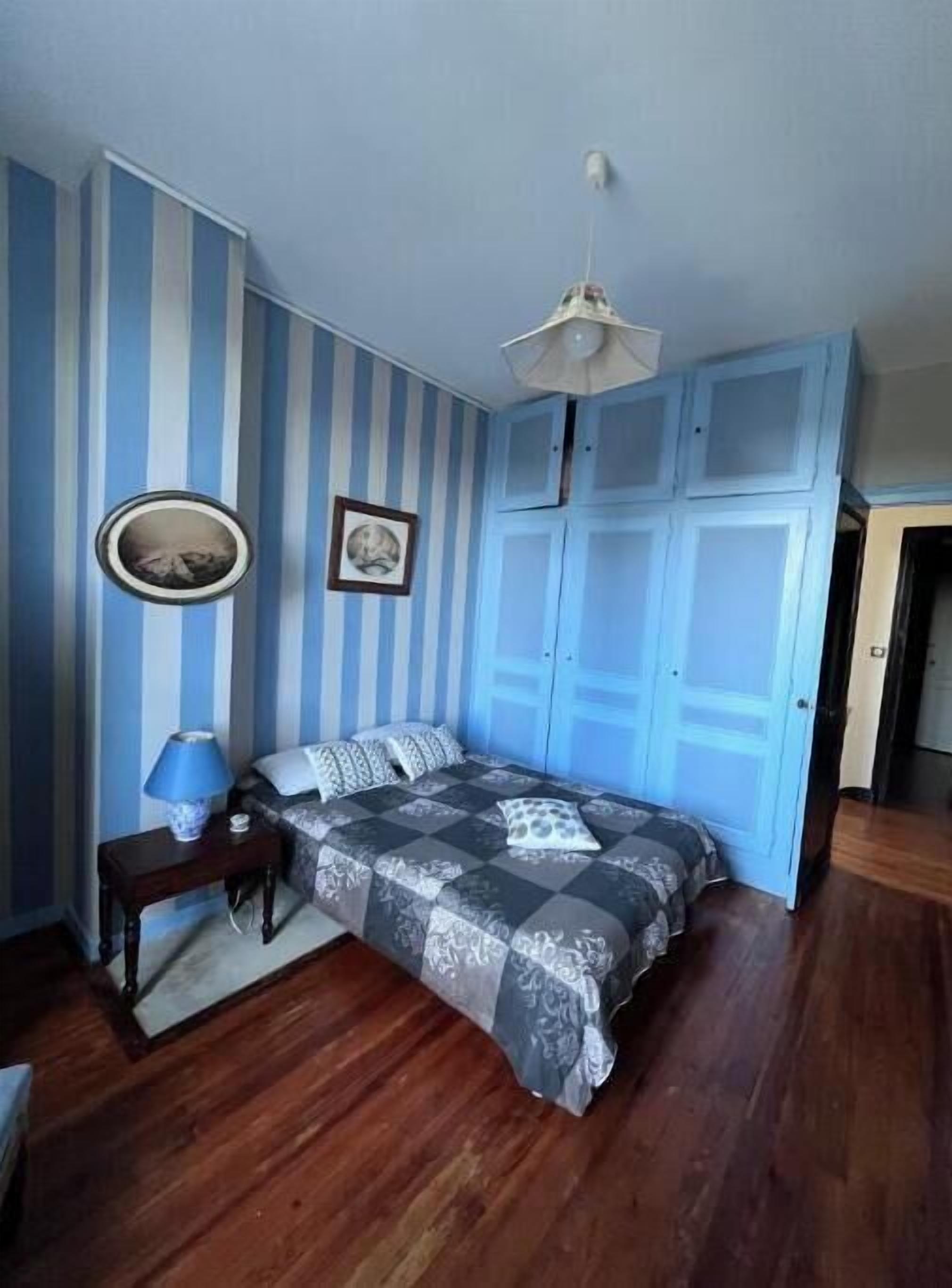 A bedroom with a bed, a bedside table, a lamp, and a ceiling fan.