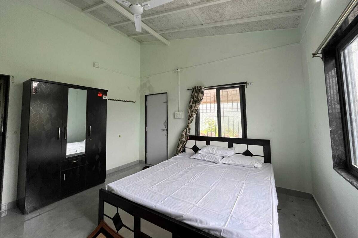 Quarto com cama, guarda-roupa, ventoinha no teto, janela e porta.