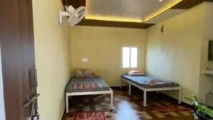 Um quarto com cama, uma mesinha e um ventilador de teto.