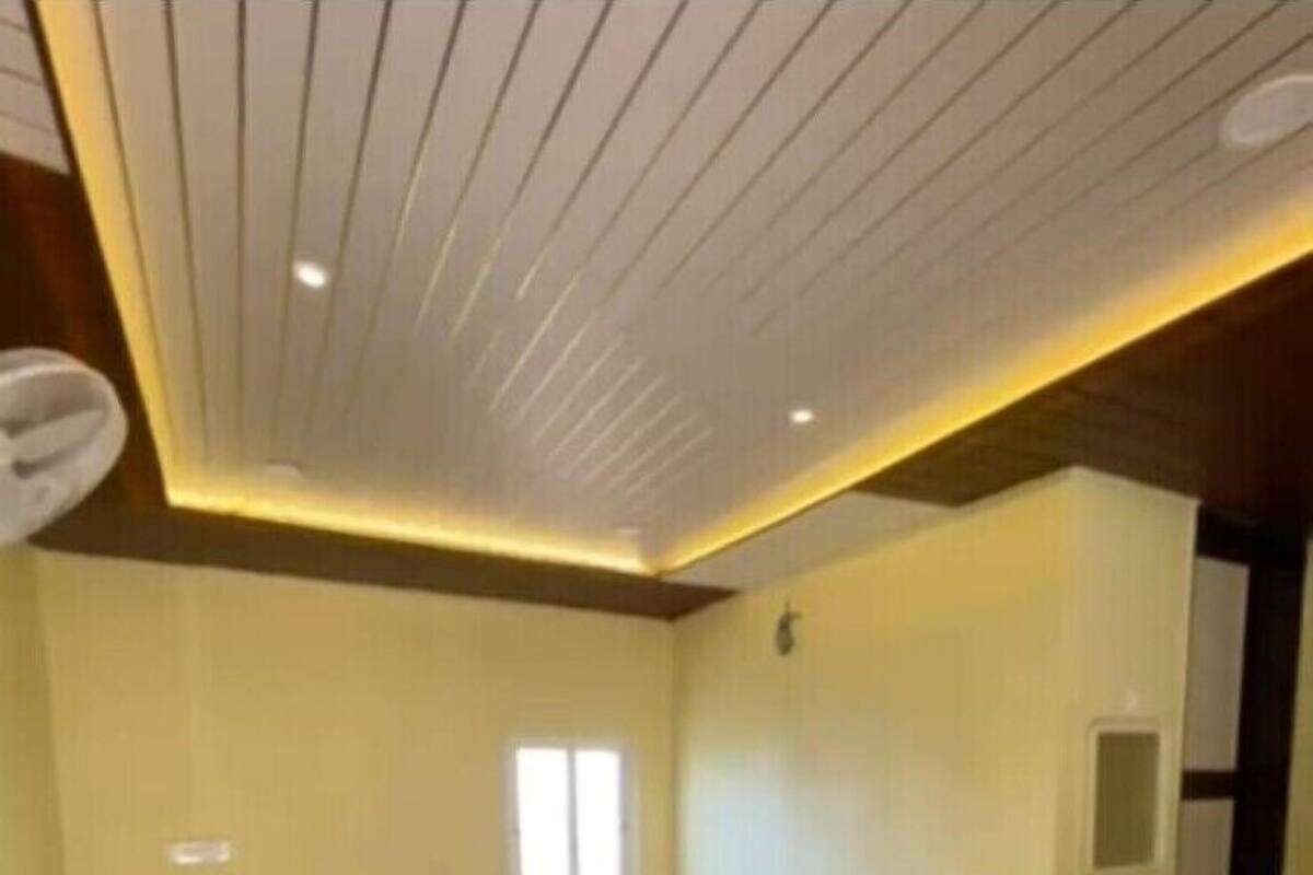 Quarto com duas camas de solteiro, uma janela pequena, pia e espelho.