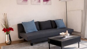 A modern living room with a grey sofa, a coffee table, and abstract wall art. - Luxury apartment - Charming 2 room apartment (Augsburg)