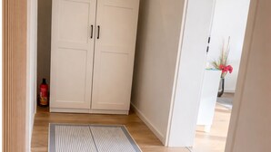 A hallway with a wooden floor, a white door, and a patterned rug. - Luxury apartment - Charming 2 room apartment (Augsburg)