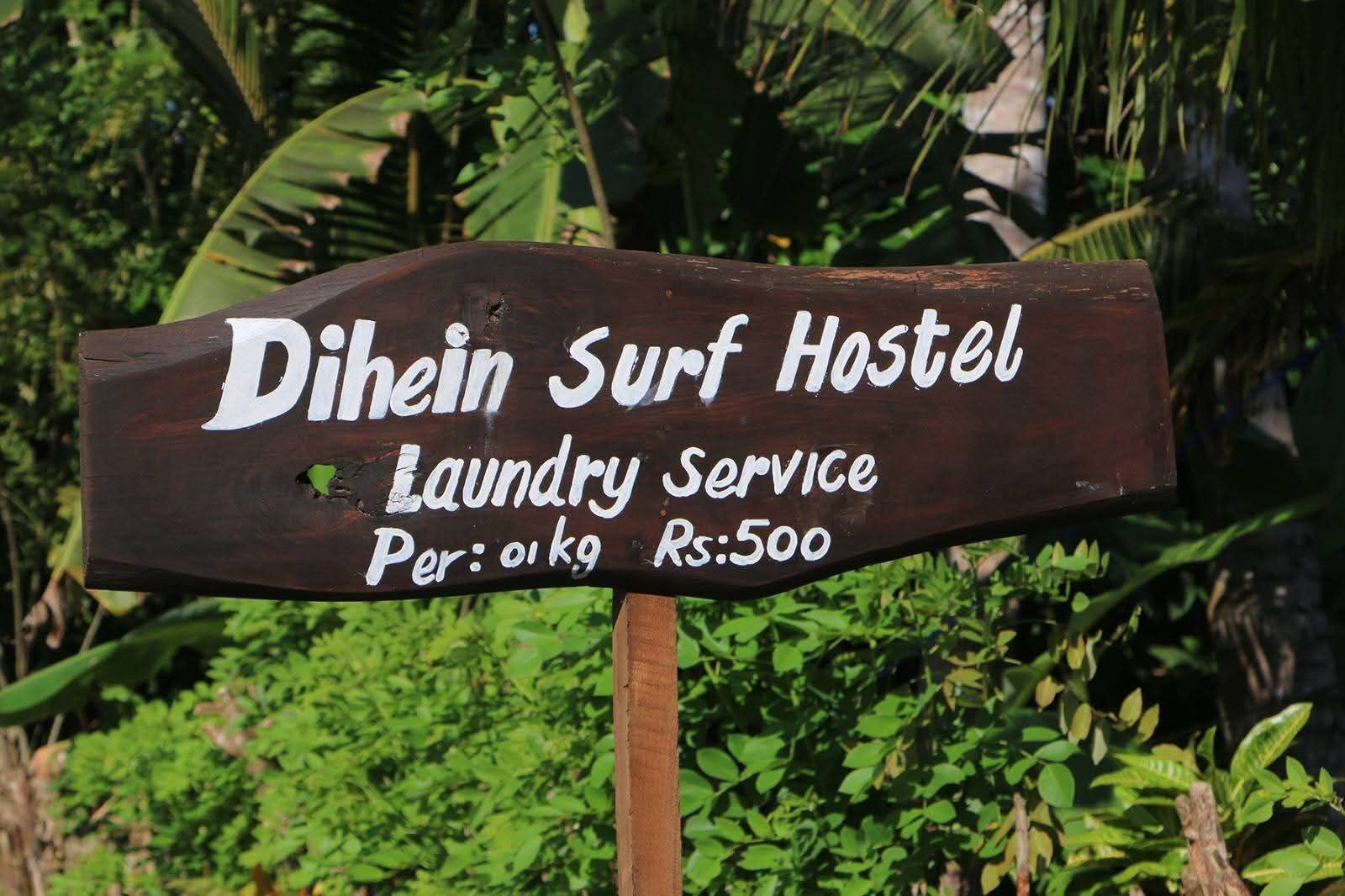 A wooden sign for Dihein Surf Hostel advertising laundry service at Rs.500 per 1kg.