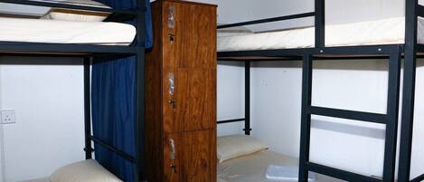 Quarto com beliche, guarda-roupa de madeira e cortina azul.