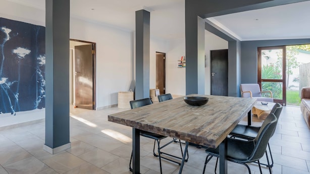Un comedor amplio con una gran mesa de madera, sillas negras y un diseño de interiores moderno.