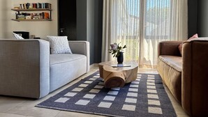 Una sala de estar moderna con un sofá gris, un sofá marrón, una mesa de centro con un jarrón y una estantería junto a la pared.