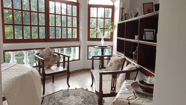 Ein Zimmer mit einem großen Bogenfenster, einem runden Tisch mit einer Vase und einem Bücherregal.