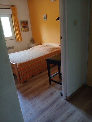 Une chambre à coucher avec un lit, une chaise, une table de chevet et une horloge murale.