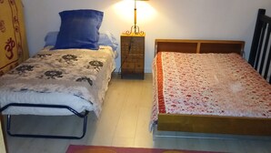 Ein Schlafzimmer mit zwei Betten, einem Nachttisch mit Lampe, einem farbenfrohen Teppich und einem hölzernen Kopfteil.