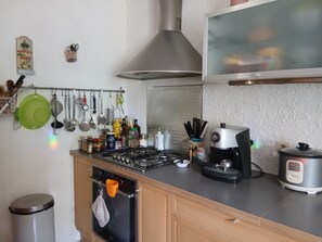 Une cuisine équipée d’une cuisinière à gaz, d’un four et de divers ustensiles accrochés au mur.