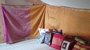 Ein Schlafzimmer mit schrägen Wänden, einem Bett mit rosa und orangefarbener Bettdecke und mehreren Kissen.