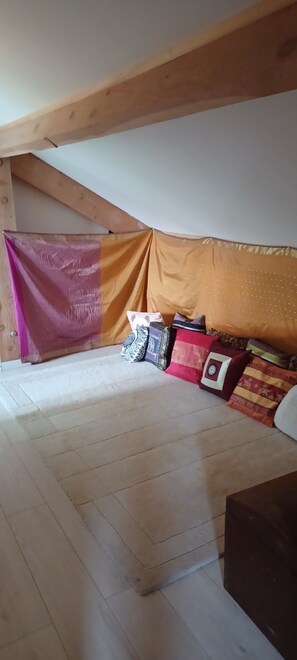 A bedroom with a sloped ceiling, a bed with a pink and orange bedspread, and several pillows. - House 6/8 persons with swimming pool in a quiet area (La Capelle-et-Masmolène)
