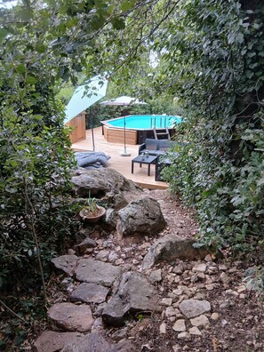 A wooden deck with a hot tub, outdoor furniture, and a stone pathway.