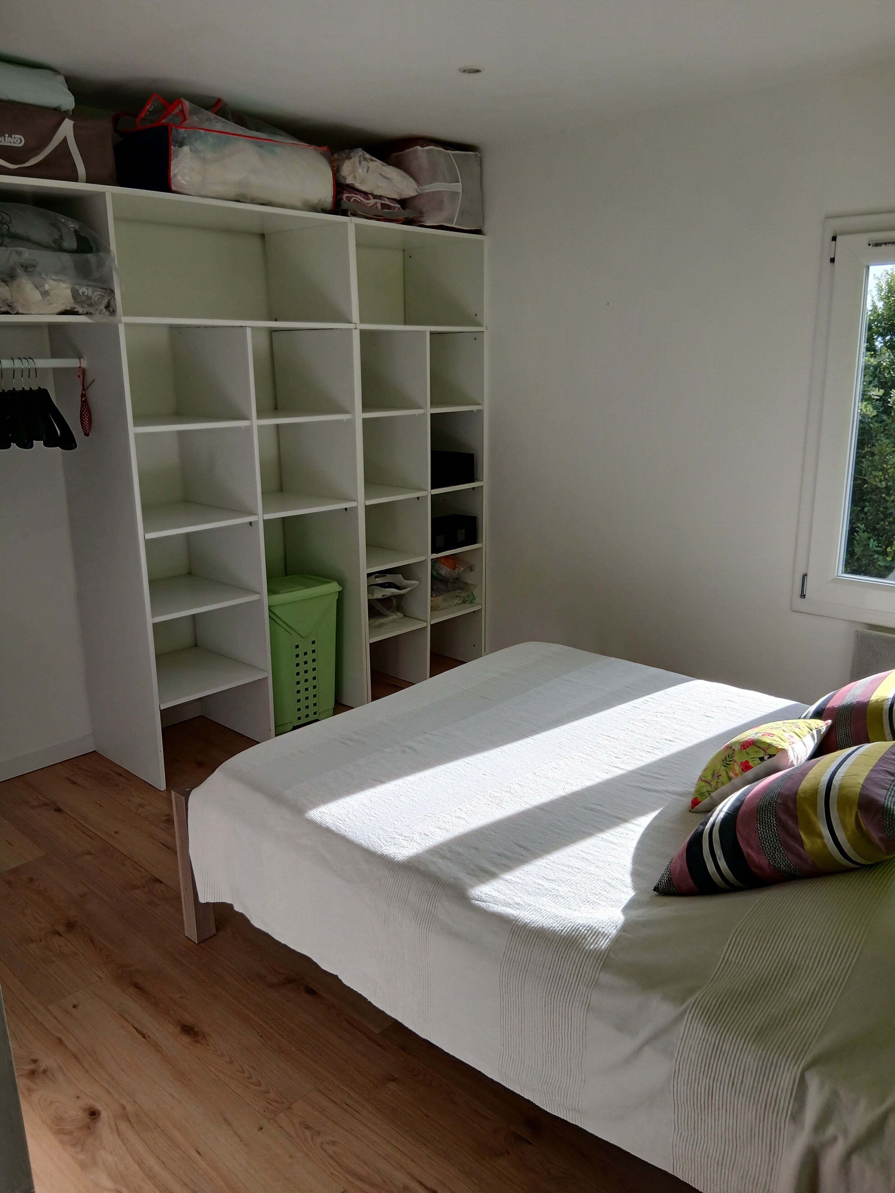 Un dormitorio con cama, armario y ventana.