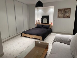 A modern bedroom with a bed, a bedside table, a mirror, and a map on the wall. - Charming, spacious (72 m²), and comfortable; 3 rooms; quiet location; near downtown (Menton)