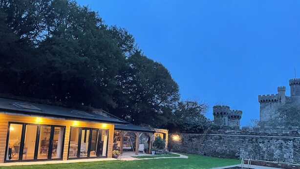A modern house with a swimming pool, a stone wall, and a castle in the background. - Private Garden House, Historic Castle Estate, Pool, Tennis & Gardens (Togher)
