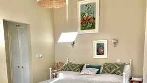 A bedroom with a large bed, a fluffy rug, a woven light fixture, and two wall-mounted light fixtures. - Private Garden House, Historic Castle Estate, Pool, Tennis & Gardens (Togher)