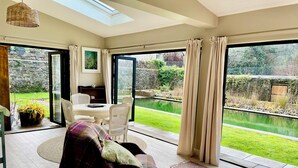 A spacious room with a large sliding glass door leading to a garden. - Private Garden House, Historic Castle Estate, Pool, Tennis & Gardens (Togher)