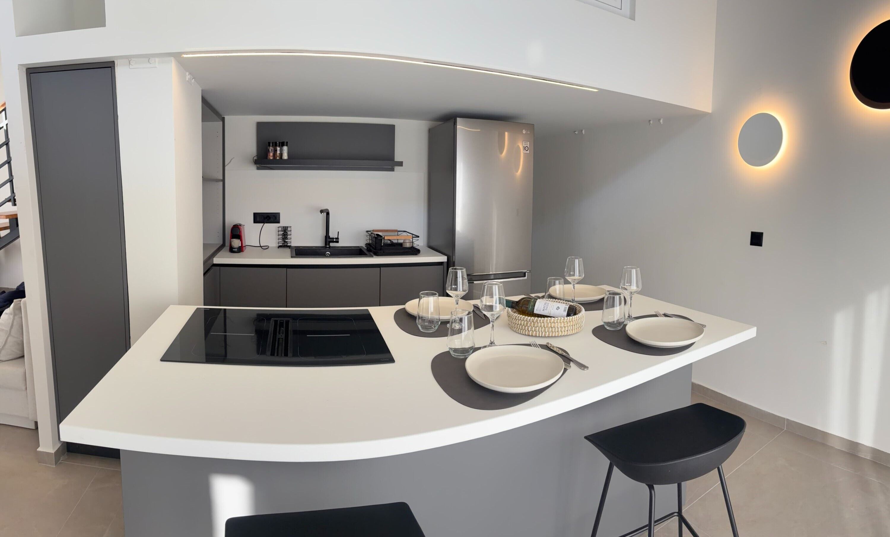A modern kitchen with a central island, a built-in oven, and a sink.