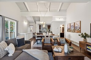 Amplia sala de estar con un sofá grande, una mesa de centro y un comedor al fondo.