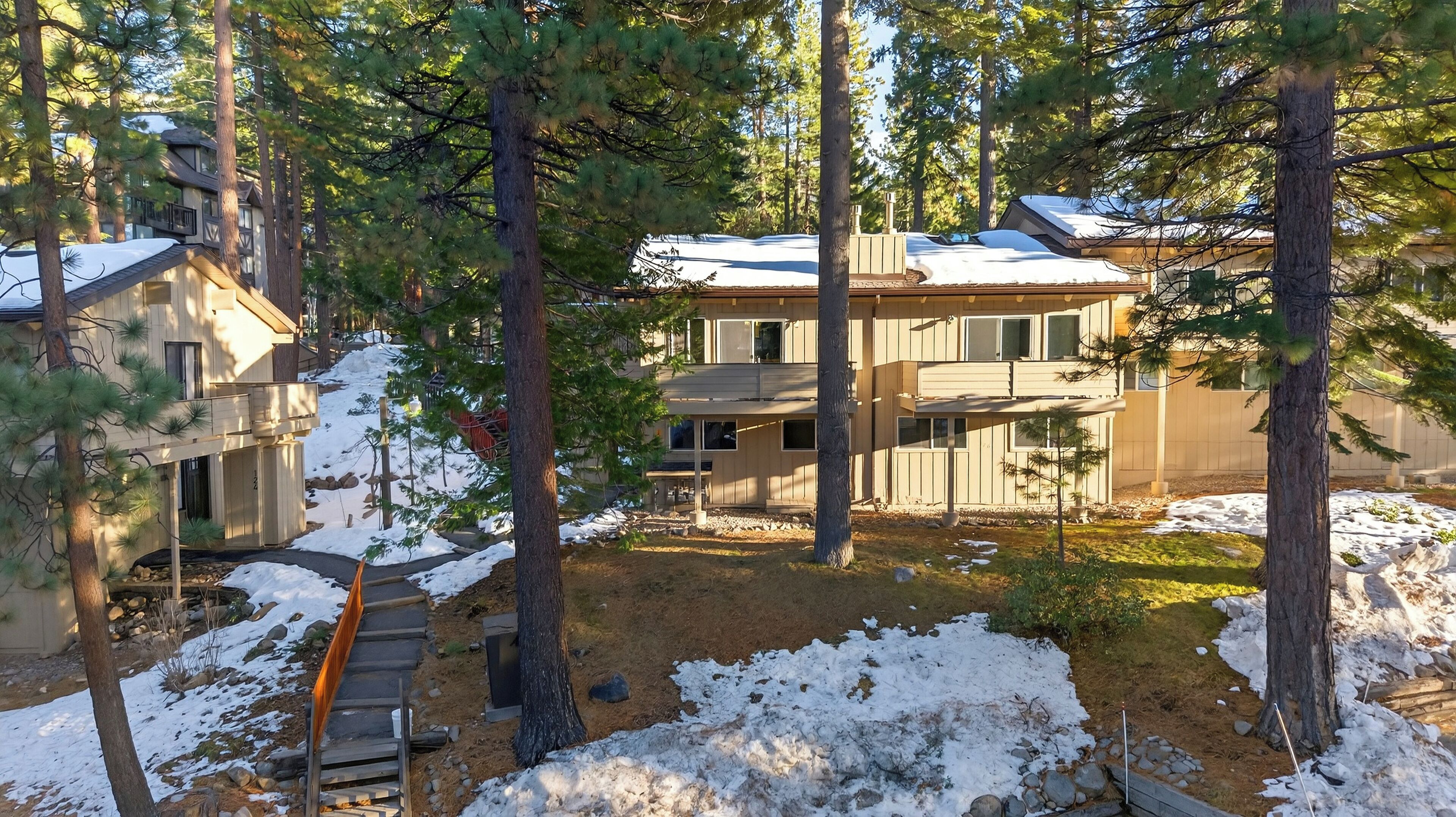 Ein zweistöckiges Haus mit einer überdachten Terrasse und einer Holzterrasse.