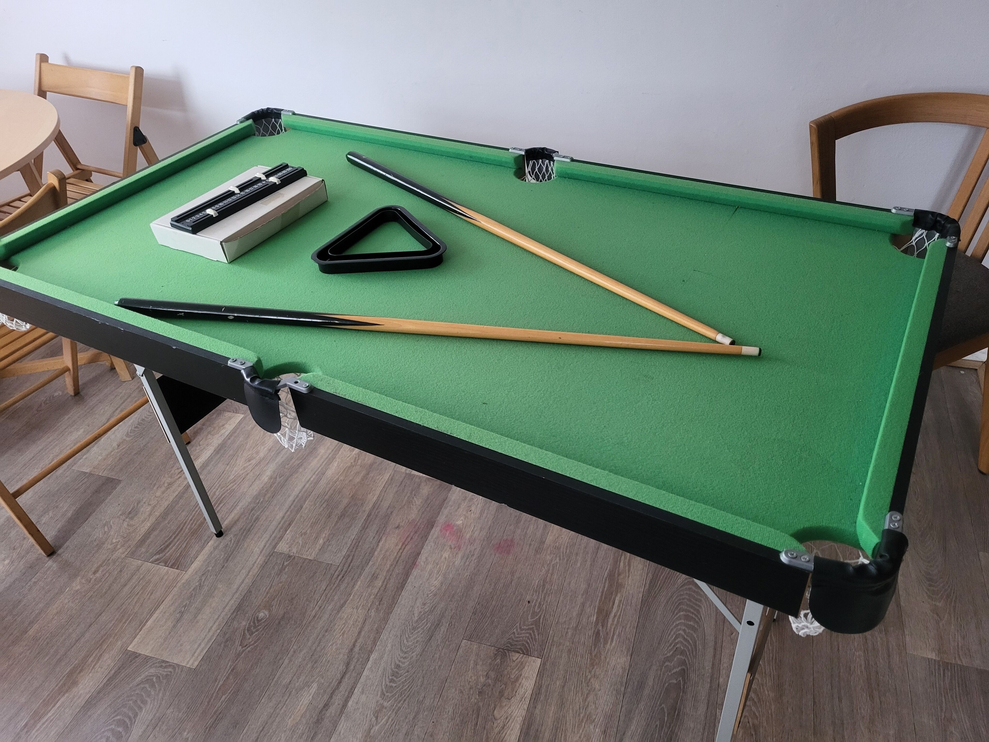 A pool table with pool cues, a cue ball, and a triangular rack.