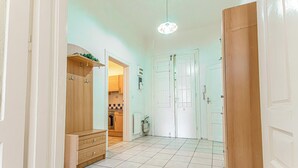 A hallway with a wooden wardrobe, a tiled floor, and a door leading to a kitchen. - Modern Stay in the Heart of the City (Vienna)