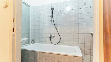 Eenvoudige kamer | Badkamer | Een bad/douchecombinatie, gratis toiletartikelen, een haardroger