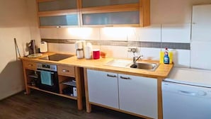 Une cuisine compacte avec des meubles en bois, un lave-vaisselle encastré et un four à micro-ondes.