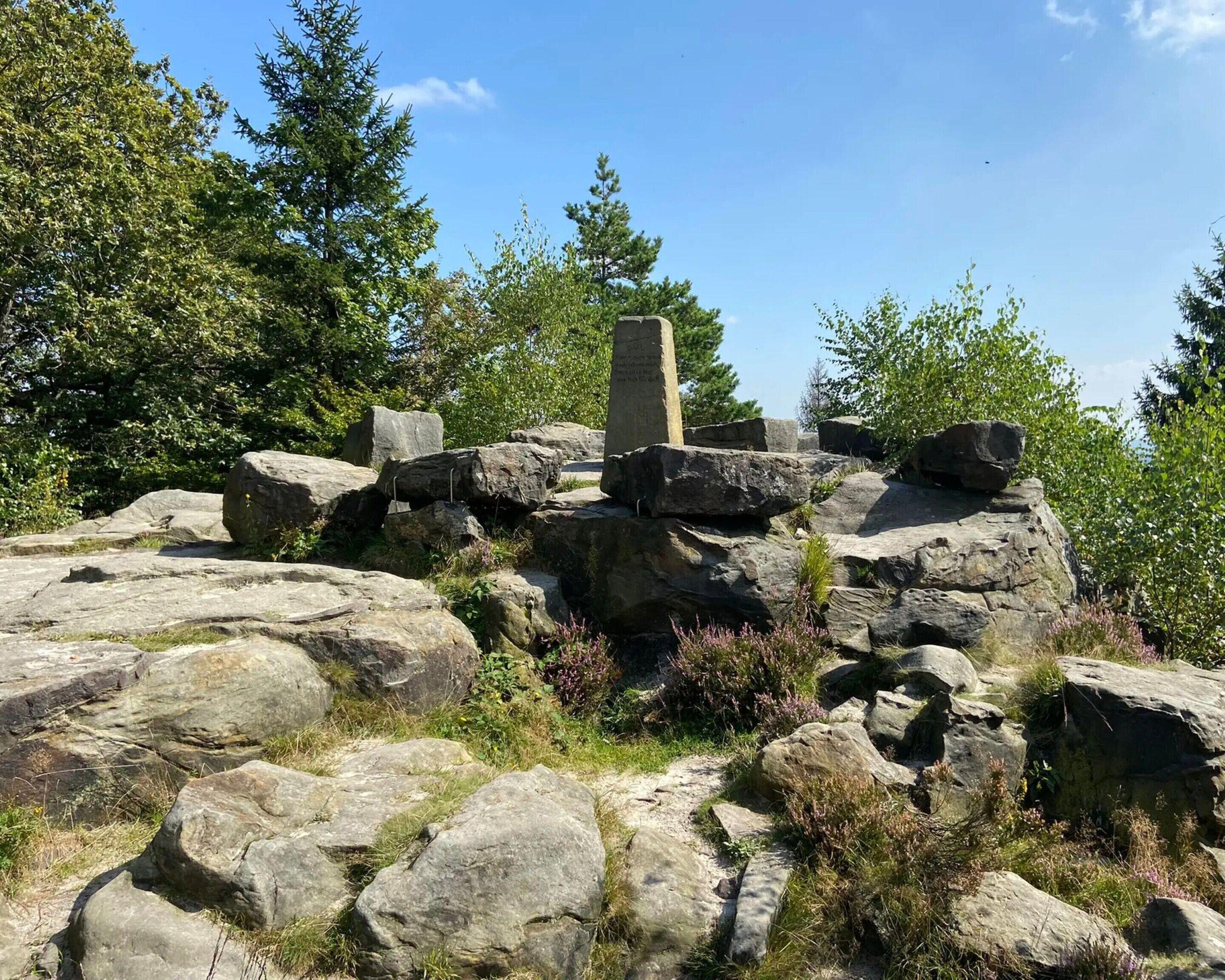 Un monumento de piedra rodeado de grandes rocas y vegetación.