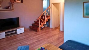 Un salon avec un escalier en bois, un téléviseur à écran plat et un canapé.