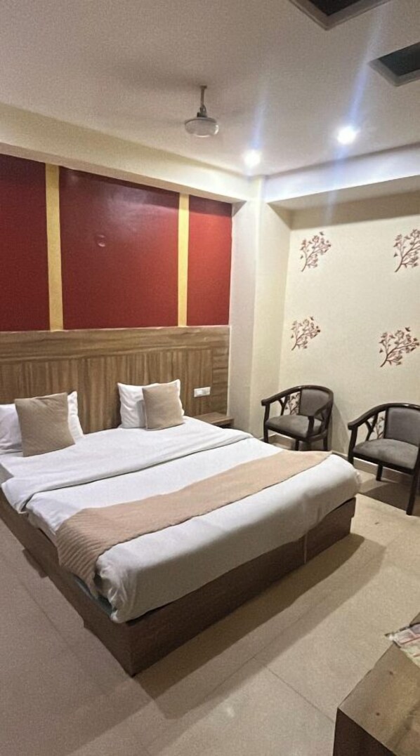 A hotel room with a large bed, two chairs, a wooden headboard, and floral wall decals.