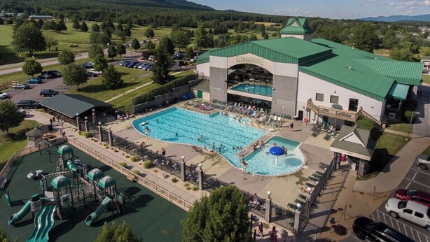 Ein großes Gebäude mit Schwimmbad, Wasserpark und Parkplatz.