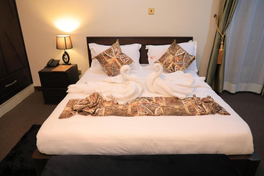 A neatly made bed with white linens, two decorative pillows, and a blanket with a geometric pattern.