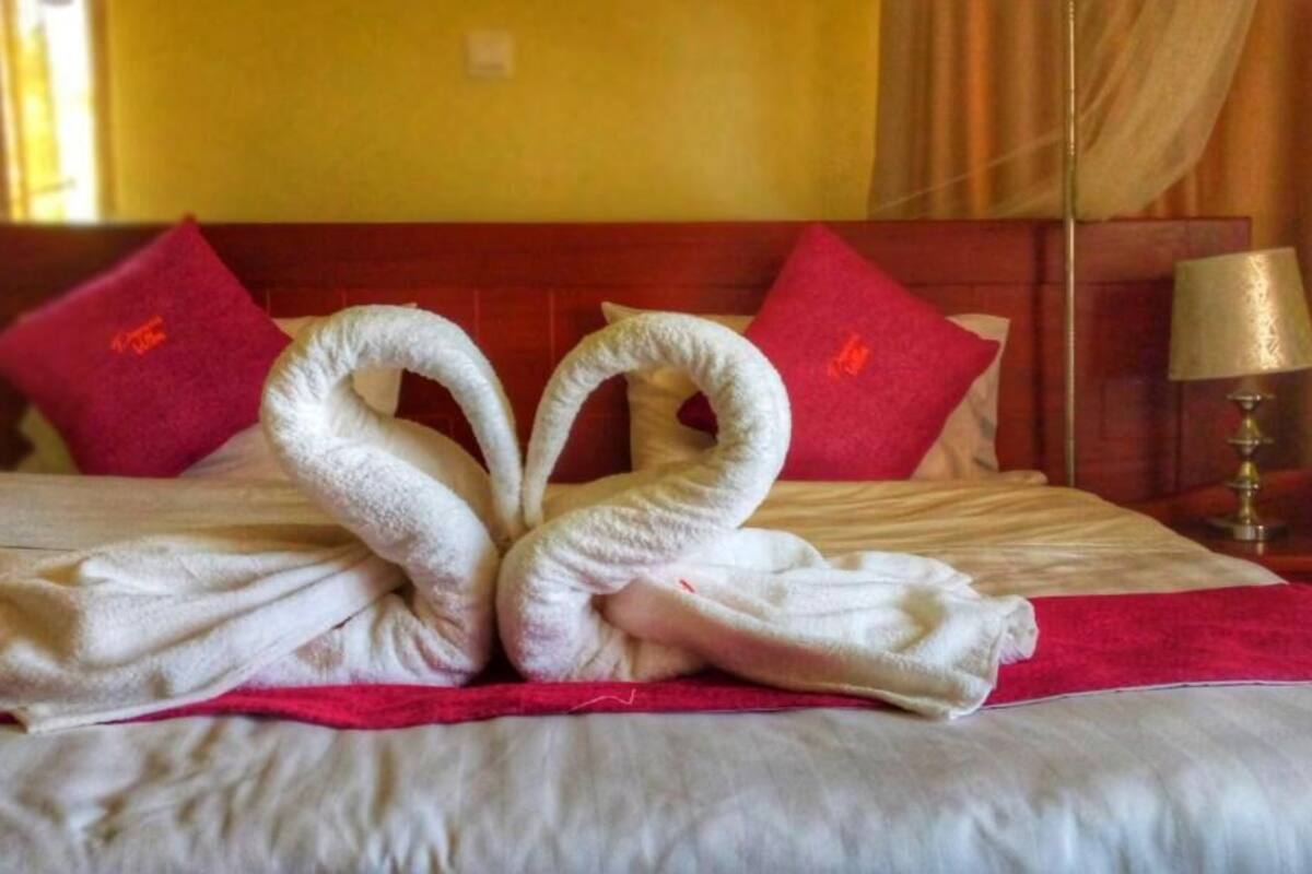 A bed with a red blanket and pillows, a wooden headboard, and a bedside lamp.