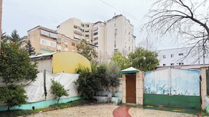 Un patio con un sendero adoquinado, una verja verde y una estructura amarilla.