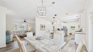 A spacious living area with a dining table, sofa, and kitchen in the background. - Rolling Retreat 77–Gulfview Escape–Sleeps 16 (Santa Rosa Beach)