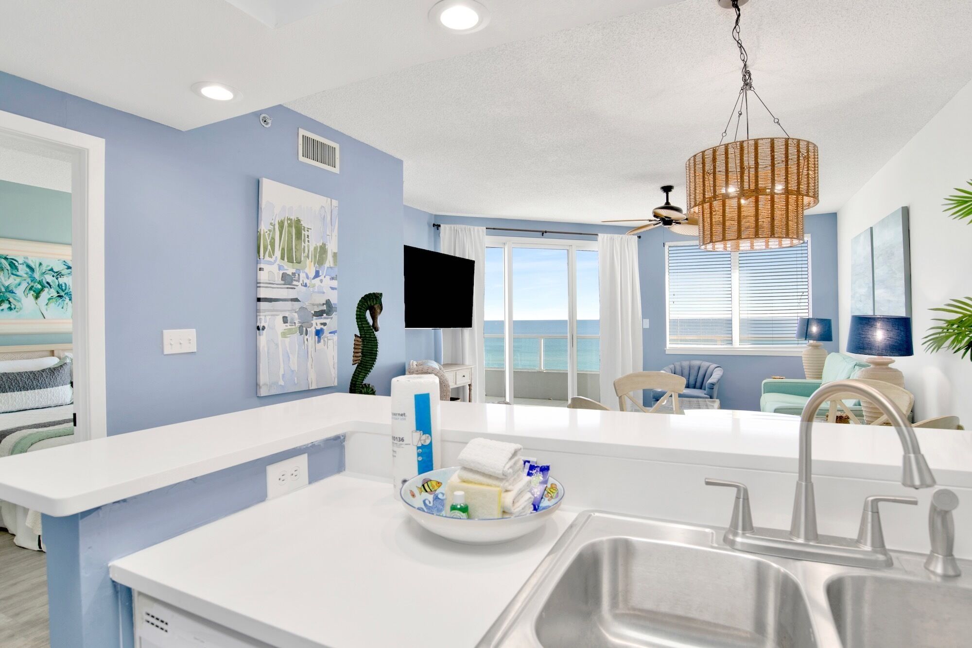A modern kitchen with a central island, a sink, and a dining area with a view of the ocean.
