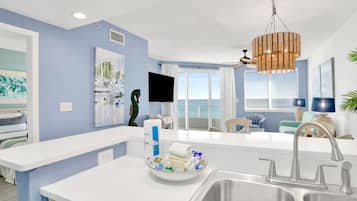 A modern kitchen with a central island, a sink, and a dining area with a view of the ocean.