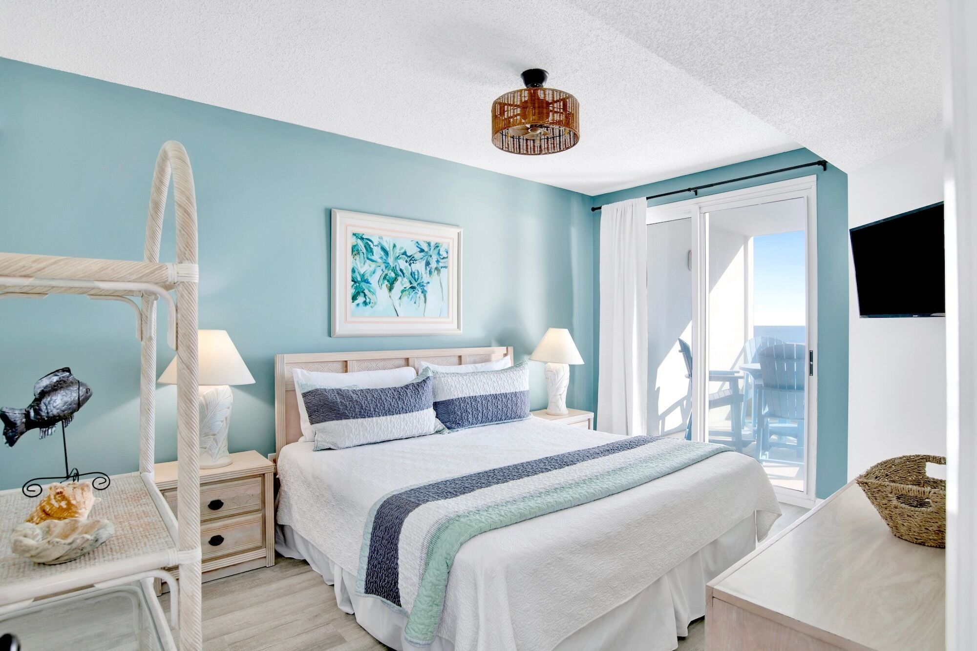 A bedroom with a bed, bedside tables, a hanging chair, a television, and a window with curtains.