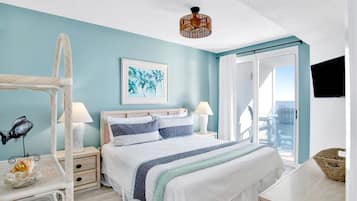 A bedroom with a bed, bedside tables, a hanging chair, a television, and a window with curtains.