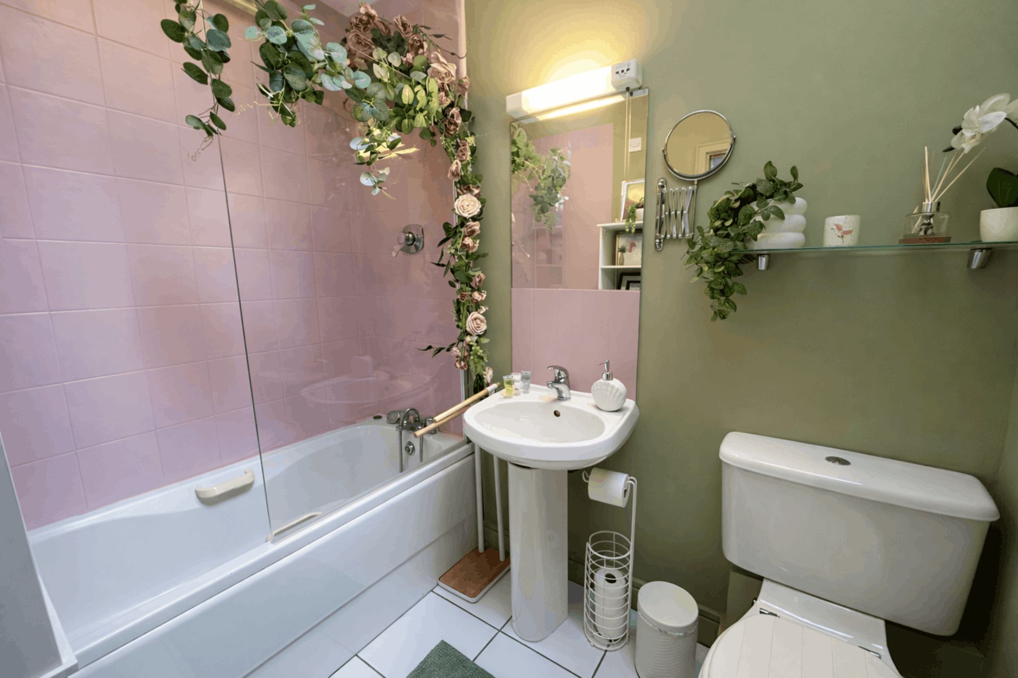A bathroom with a bathtub, sink, toilet, and decorative plants.