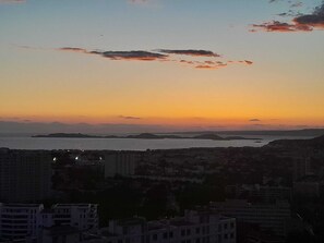 Un paisaje urbano al anochecer, con edificios y una masa de agua en la distancia.