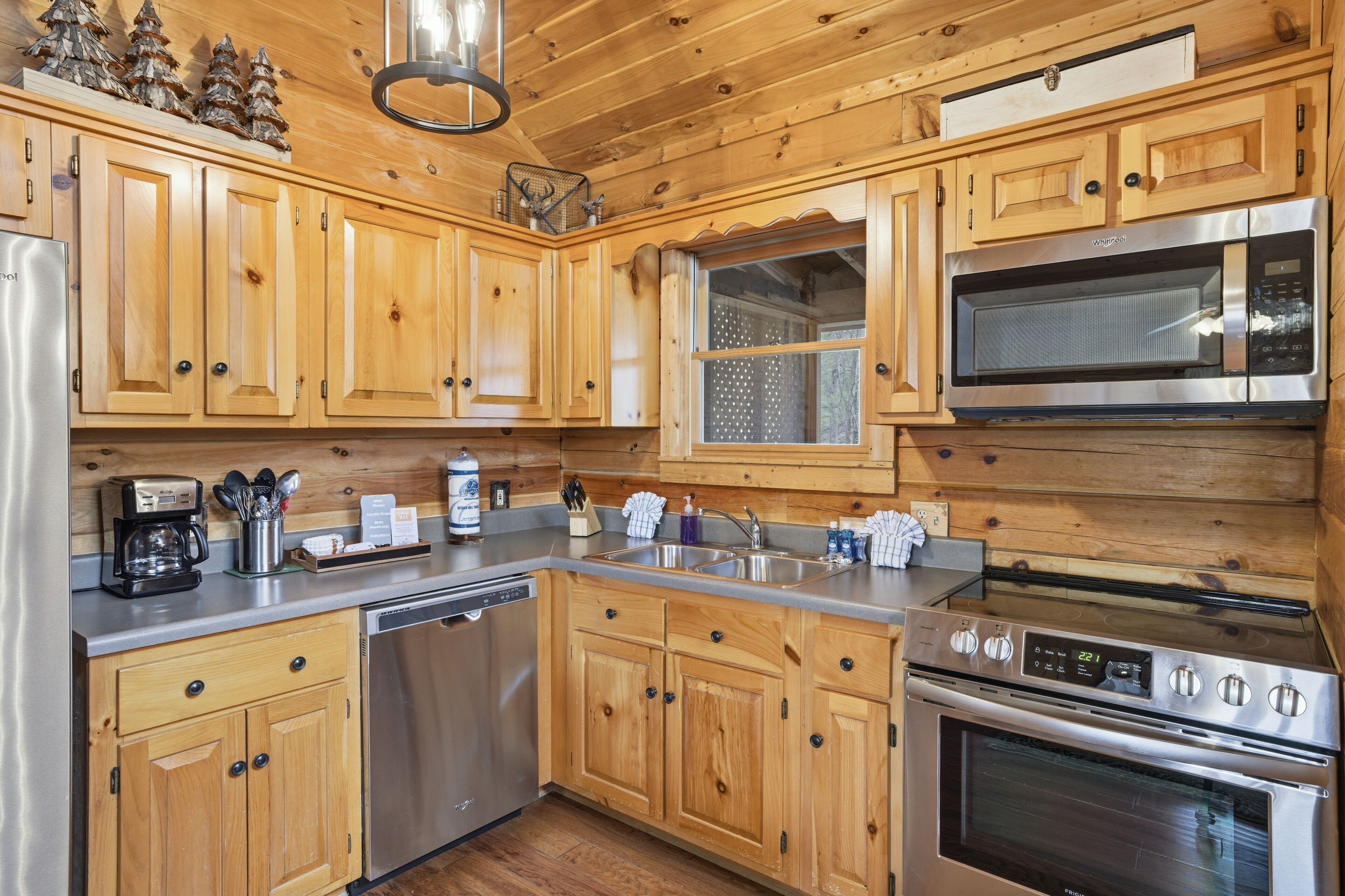 A kitchen with wooden cabinets, stainless steel appliances, a coffee maker, and a window with a view.