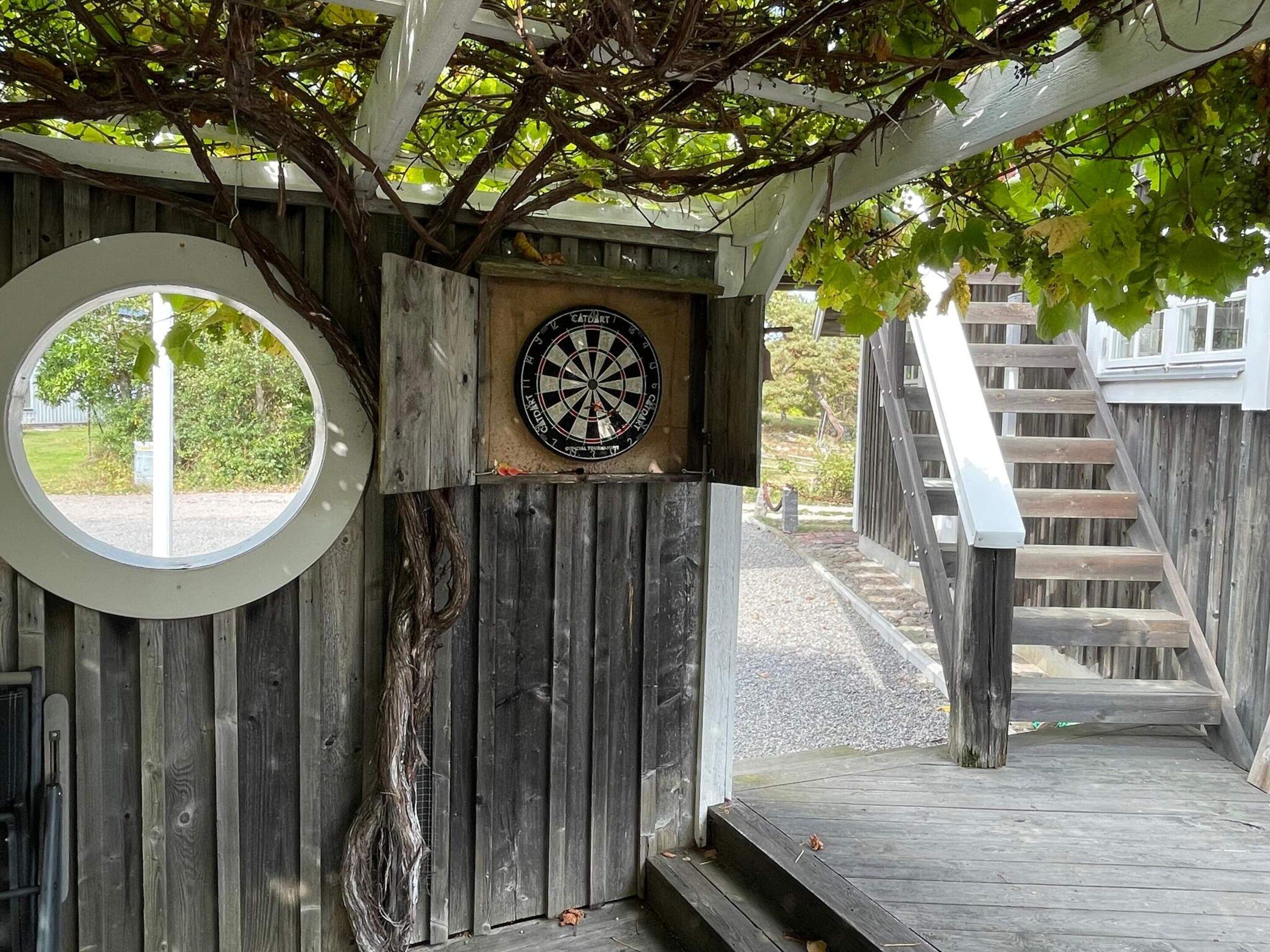 Una estructura de madera con un dardo en la pared, un ventanal circular y una escalera de madera.