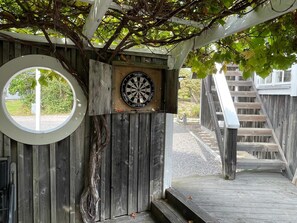 Una estructura de madera con un dardo en la pared, un ventanal circular y una escalera de madera.